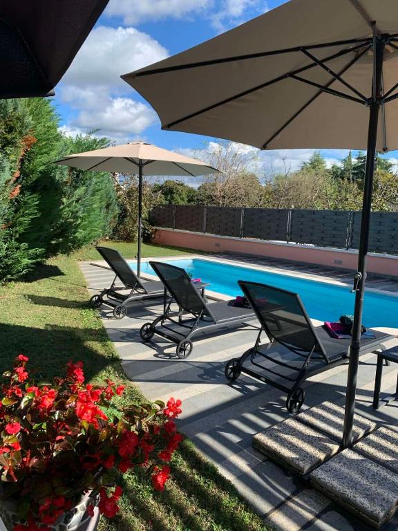 a group of chairs and umbrellas next to a pool at Holiday Home Natasha in Svetvinčenat