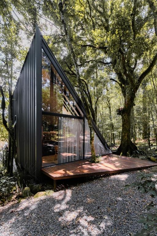 a modern house in the woods with a wooden deck at Arau Cabana Cheiro de Mato in Flores da Cunha