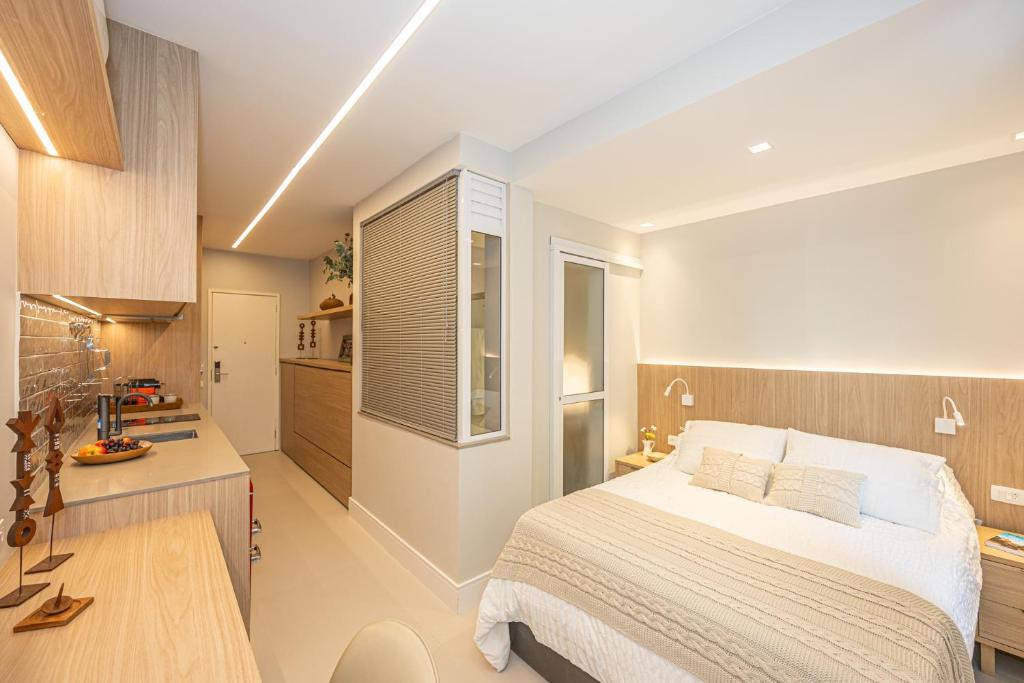 a bedroom with a bed and a desk and a kitchen at sweet ipanema Studio in Rio de Janeiro