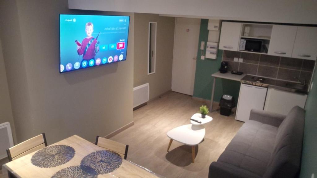 - un salon avec un canapé et une télévision murale dans l'établissement Appartement 5 - Hyper centre - 1 à 4 personnes, à Douai
