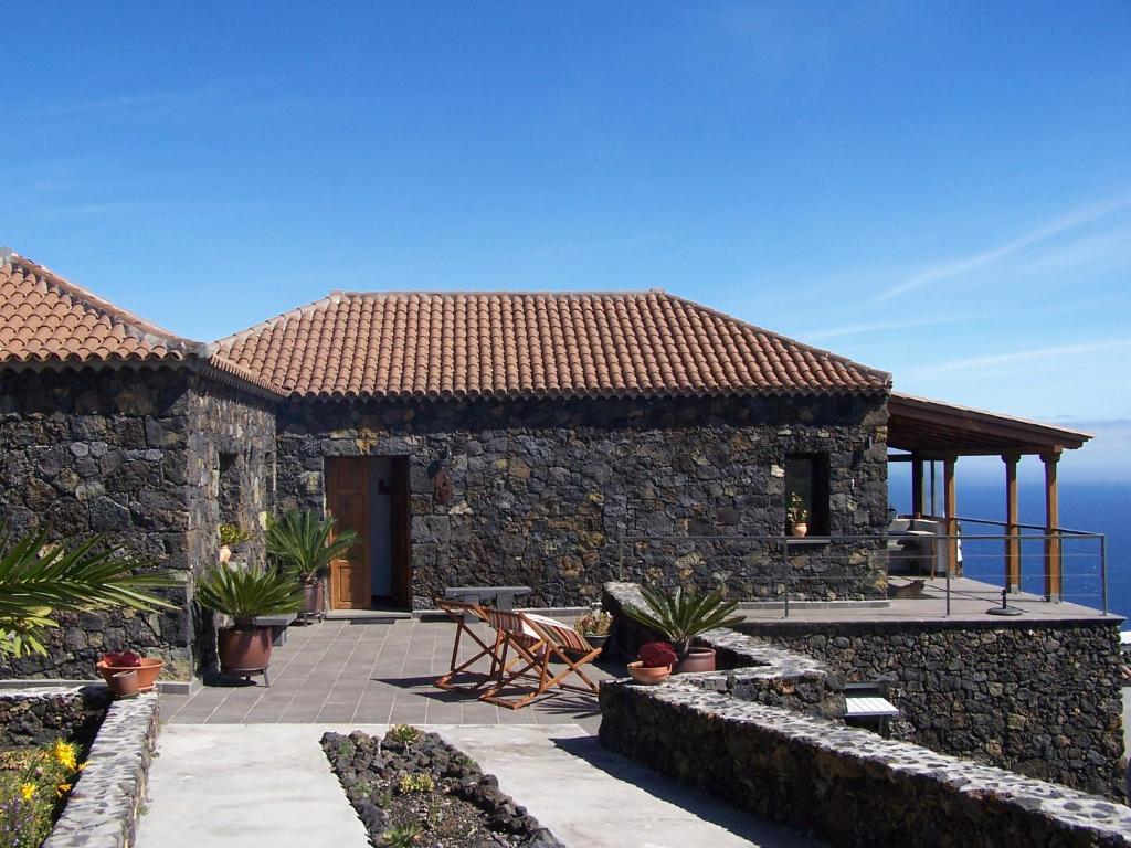 a stone house with a patio and the ocean in the background at Casa El Mirador in Fuencaliente de la Palma