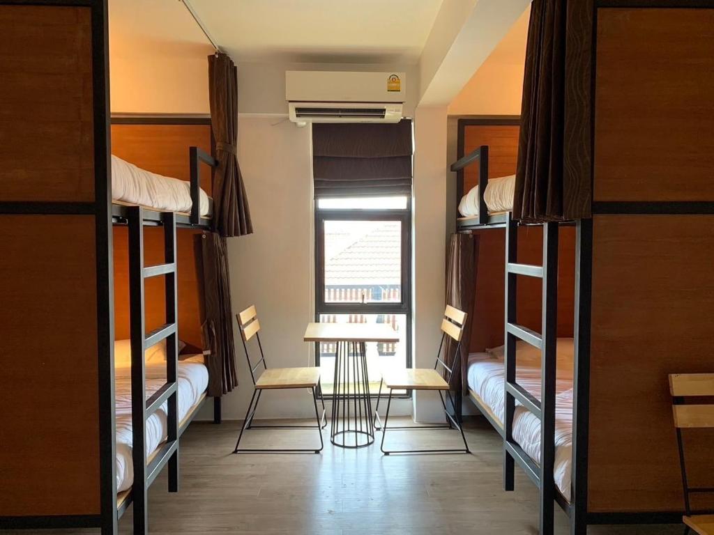a room with bunk beds and a table and chairs at Lazy Gibbon 2 Chiang Mai - Haiya in Chiang Mai