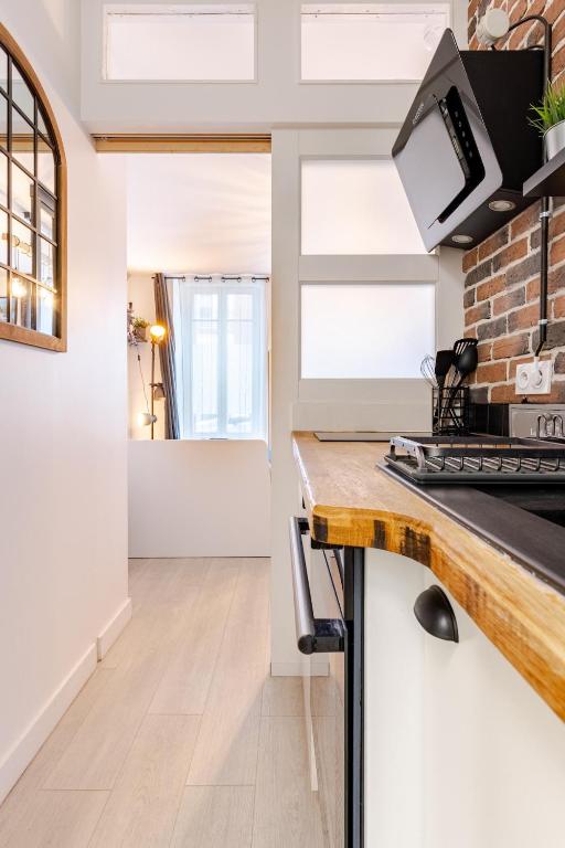 - une cuisine avec des murs blancs et un mur en briques dans l'établissement Escale à Clisson - L'atelier, à Clisson