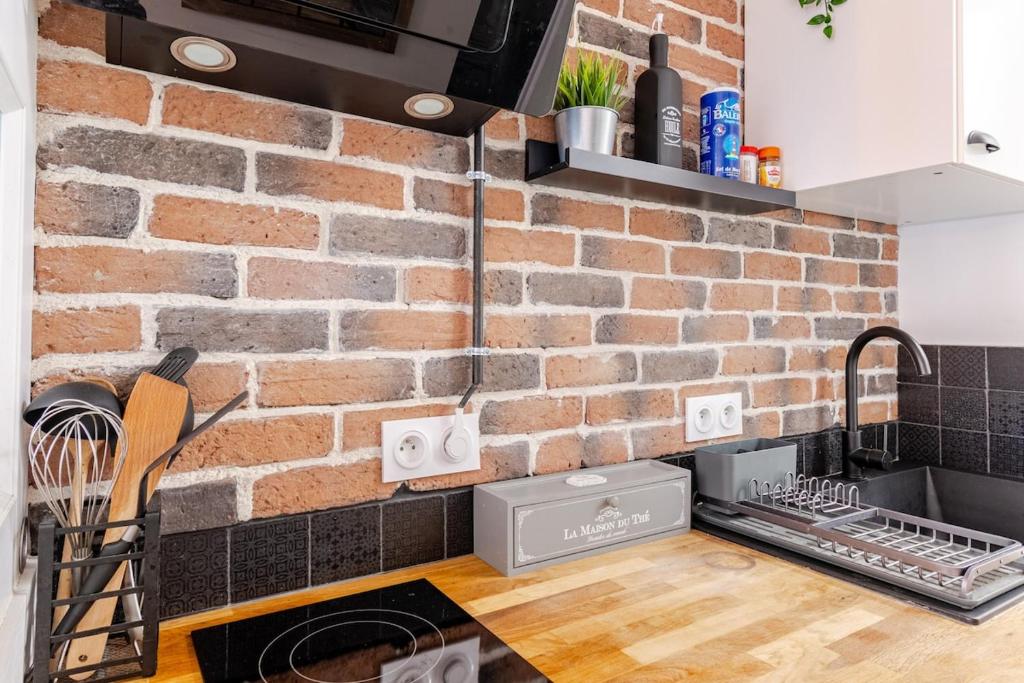 a brick wall in a kitchen with a sink at Escale à Clisson - L'atelier in Clisson
