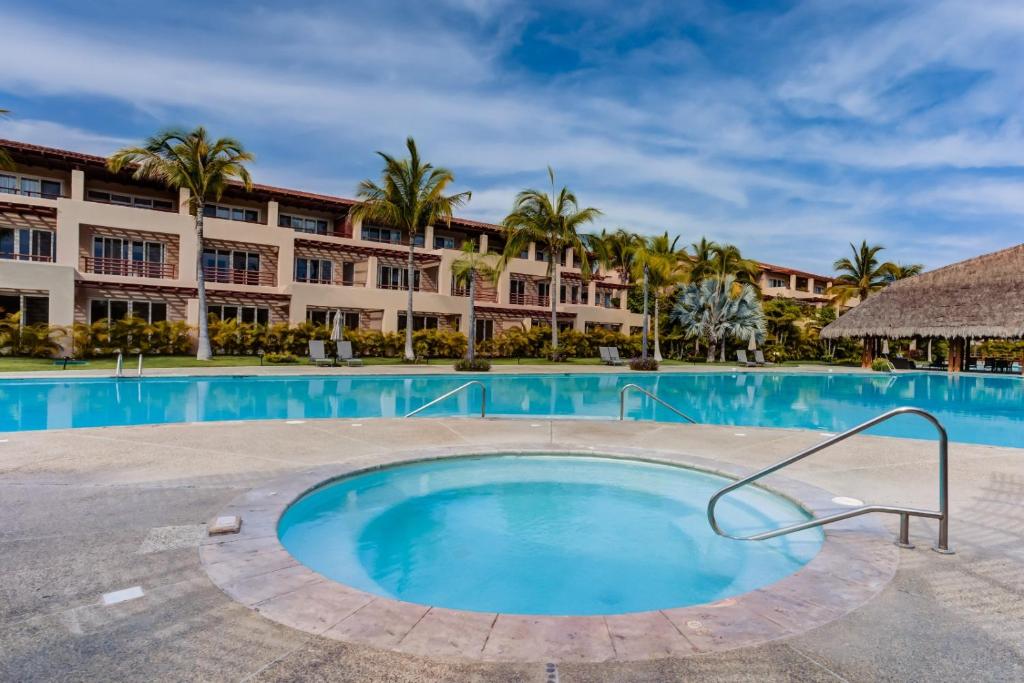 a swimming pool with a resort in the background at El Tigre, Isla Palmares with Balcony & Shared Pool in Nuevo Vallarta 