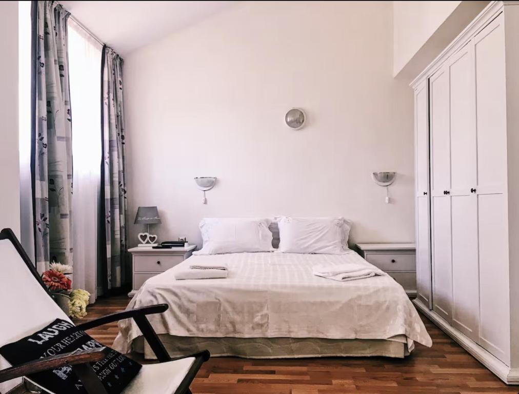 ein weißes Schlafzimmer mit einem Bett und einem Stuhl in der Unterkunft Spacious Modern Two-Bedroon Suite in Elit 1 Complex in Sonnenstrand