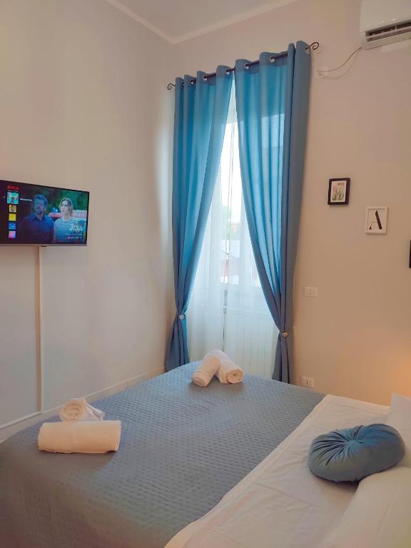 a bedroom with a bed with blue curtains and two towels at F.A.M. ROOMS in Ciampino