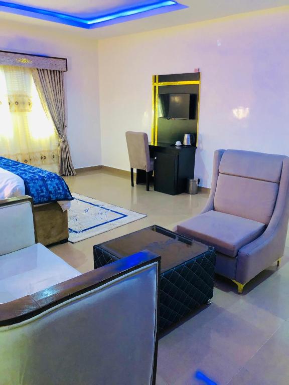 a bedroom with a bed and a couch and a chair at Udokanson Hotel And Suites in Agbor