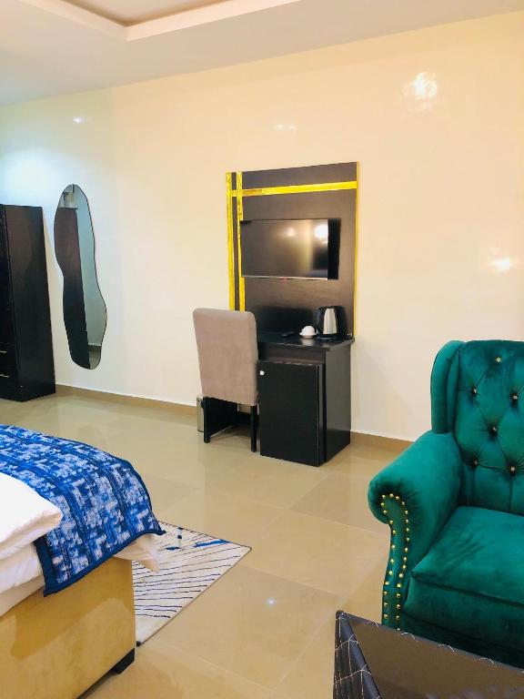 a bedroom with a bed and a chair and a desk at Udokanson Hotel And Suites in Agbor