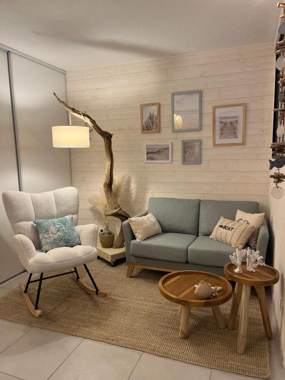 un salon avec un canapé bleu et une chaise dans l'établissement Perle des Sables Blancs, appartement entier à 100m de la plage avec parking privé, à Concarneau