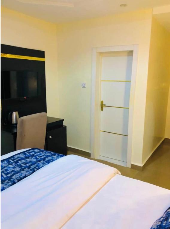 a bedroom with a bed with a door and a desk at Udokanson Hotel And Suites in Agbor