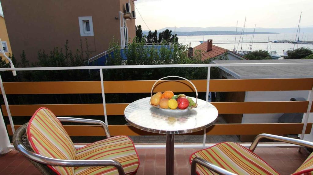 a bowl of fruit on a table on a balcony at One-Bedroom Apartment Malinska near Sea 2 in Malinska