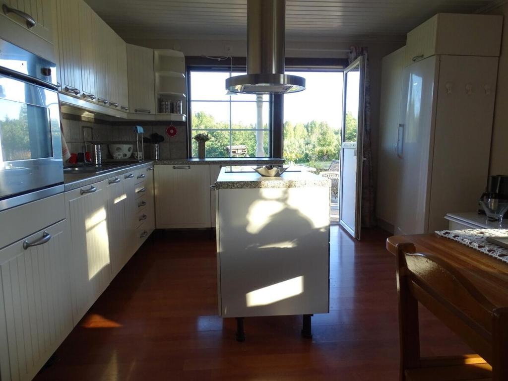 a large kitchen with white cabinets and a large window at Humlehjarta Schweden Norrbotten Ferienhaus Ferienwohnung in Överkalix