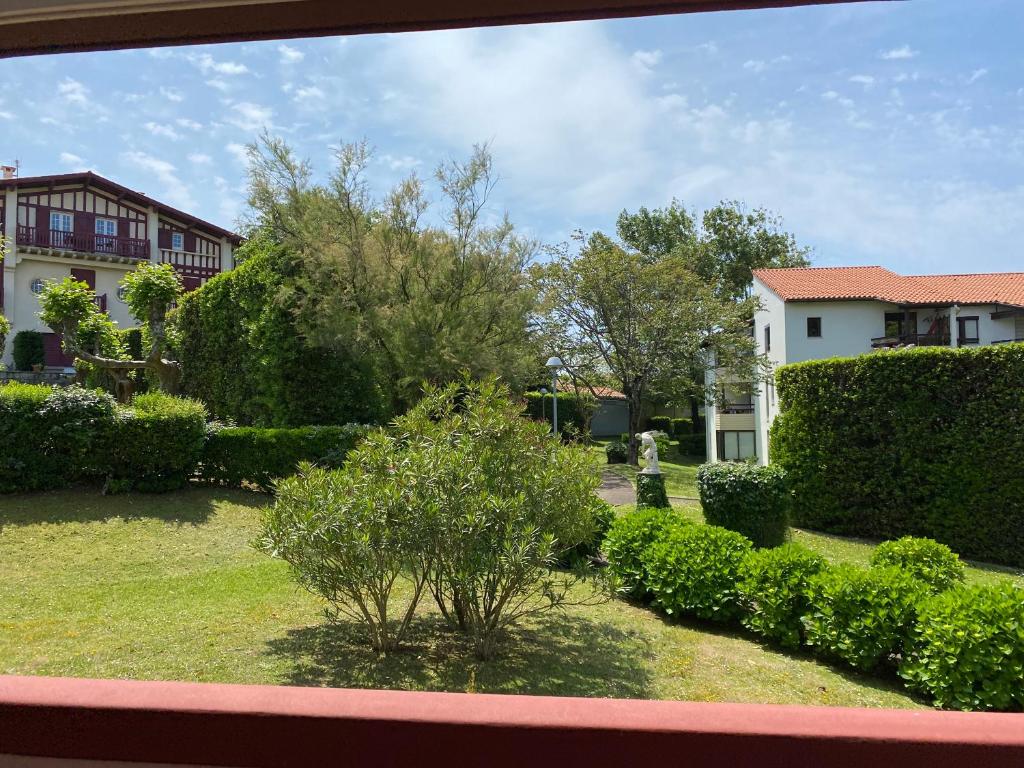 - une vue sur un jardin avec des buissons et des bâtiments dans l'établissement Nid de verdure proche océan, à Anglet