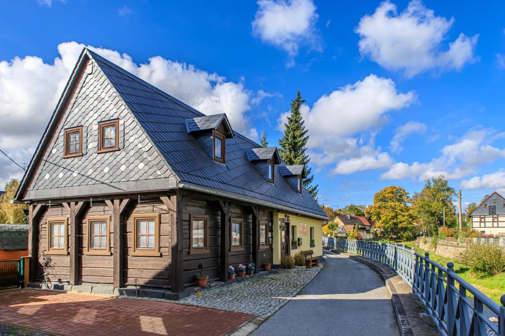a large wooden house with a blue roof at Ferienhaus Sissi - Wellness-Paradies in ruhiger Lage mit Whirlpool und Sauna in Großschönau