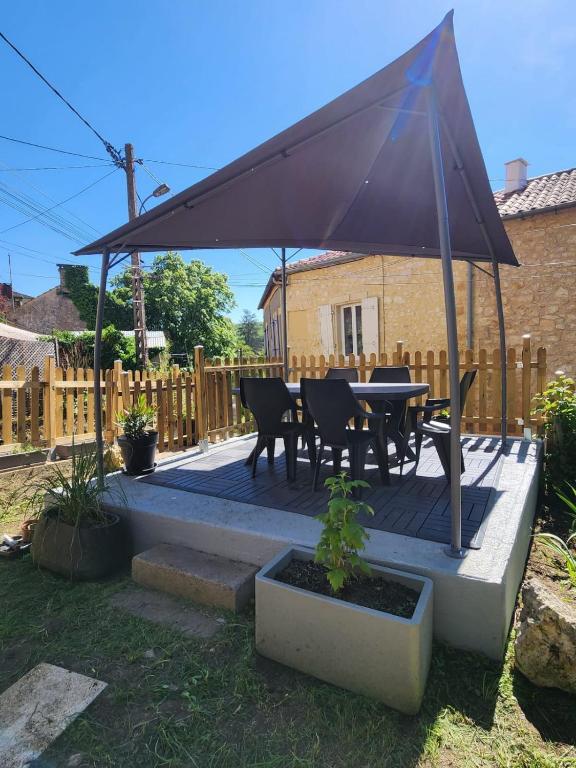 d'une terrasse avec une table et des chaises sous un auvent. dans l'établissement Gîte en Dordogne chez les Couz 'hôtes du Périgord, à Couze-et-Saint-Front