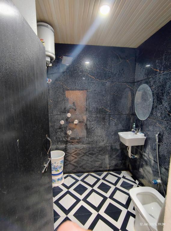 un bagno bianco e nero con servizi igienici e lavandino di Shivnandani a Ujjain