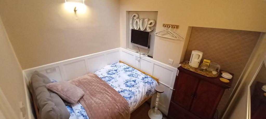 a small bedroom with a bed and a tv on the wall at Woodfield hideaway in Matlock