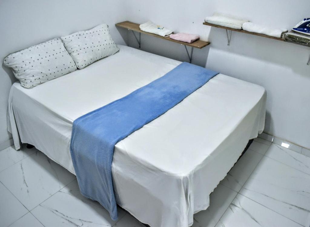 a white bed with a blue blanket on it in a room at Casa Resiliência in Itacaré