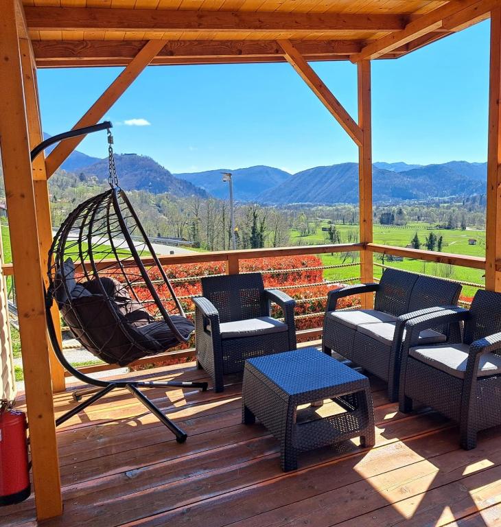 a porch with a swing and chairs on a deck at Holiday HOUSE NEAR THE SOČA RIVER in Tolmin