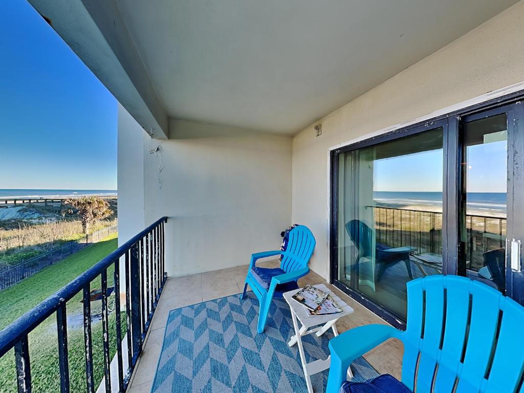 two blue chairs on a balcony with a view of the ocean at Sunkissed Escape in Jacksonville Beach