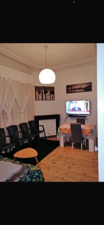 un salon avec une table, des chaises et une télévision dans l'établissement Une balade à la plage, à Dunkerque