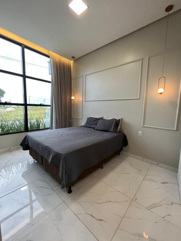 a bedroom with a bed and a large window at Casa disponível para a COP in Ananindeua