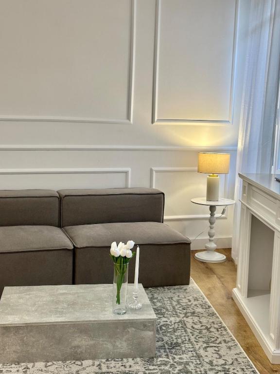 un salon avec un canapé et une table avec des fleurs dans l'établissement Appartement Nemausus XIX, à Nîmes