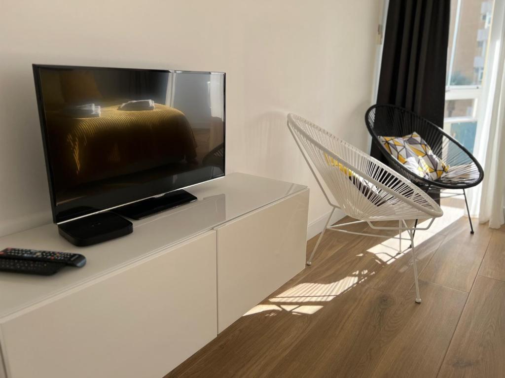 telewizor z płaskim ekranem siedzący na białej szafce w obiekcie Holiday Studio by Meatina w mieście Torremolinos