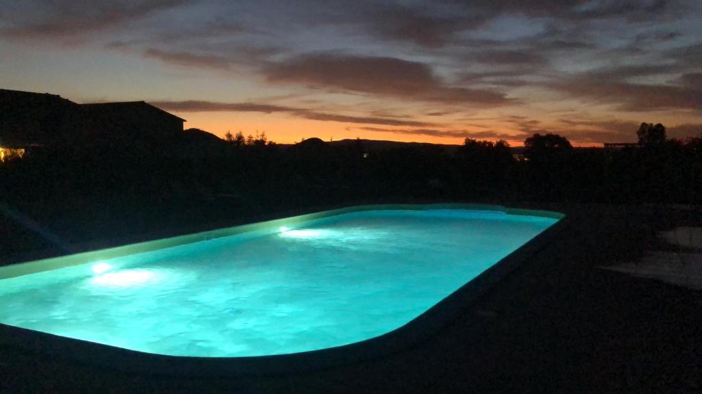 Una gran piscina azul con una puesta de sol al fondo en Maremma Toscana a Scarlino elegante appartamento, en Scarlino