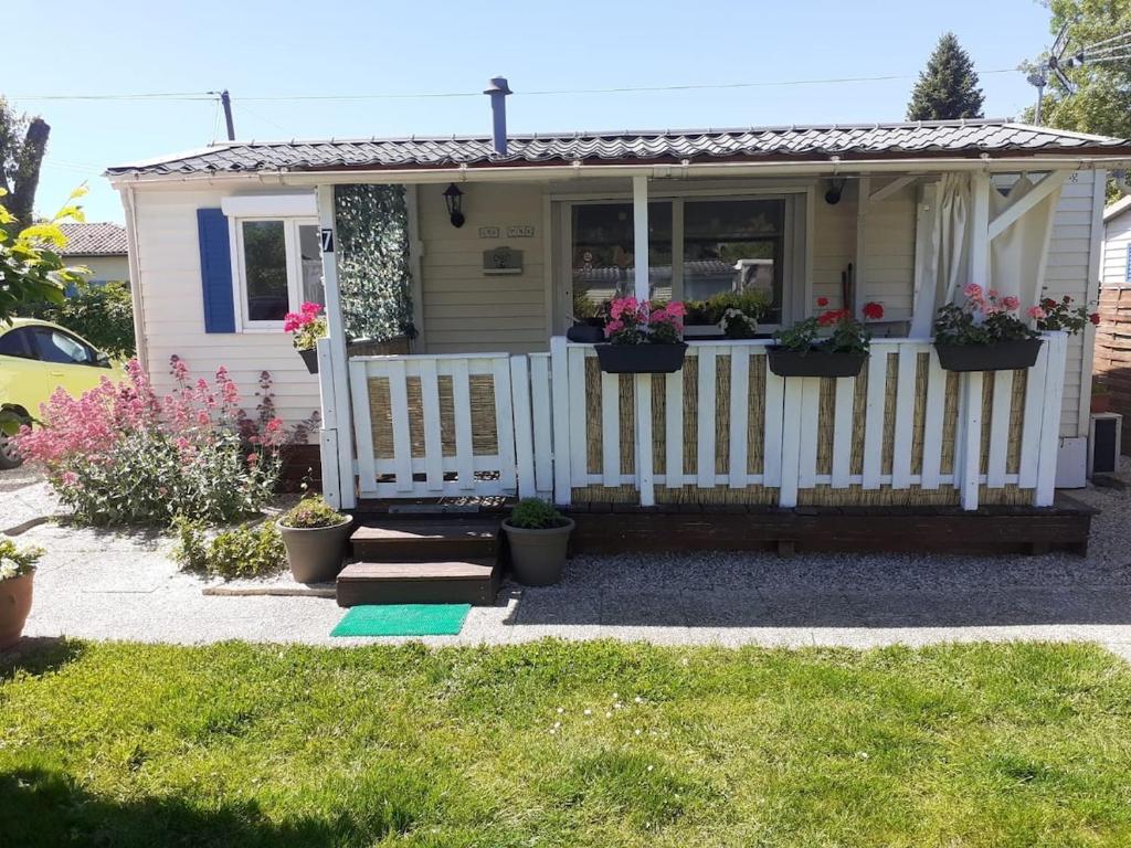 une petite maison avec une clôture blanche et des fleurs dans l'établissement LOCATION CLIM 2 CH Lac de Lougratte, à Lougratte