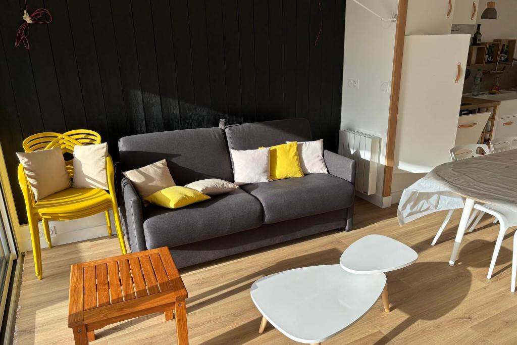 - un salon avec un canapé noir et des fauteuils jaunes dans l'établissement Appartement Kerabus proche plage, à Quiberon