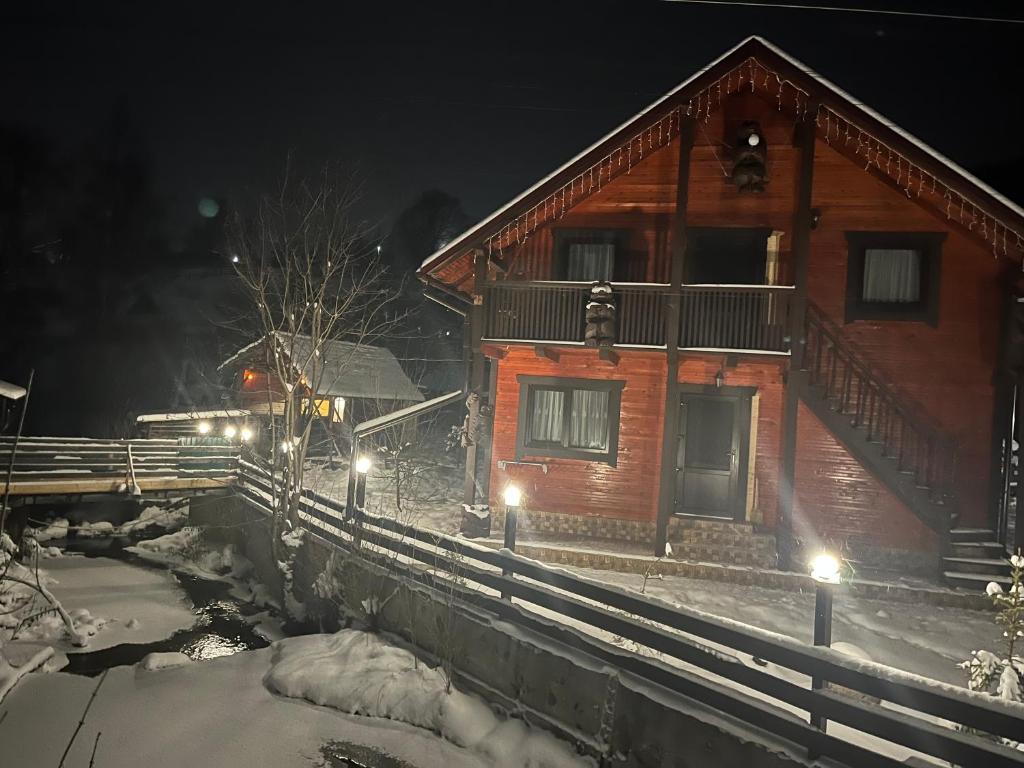 a house with a train in the snow at night at Незабутні Карпати in Vorokhta