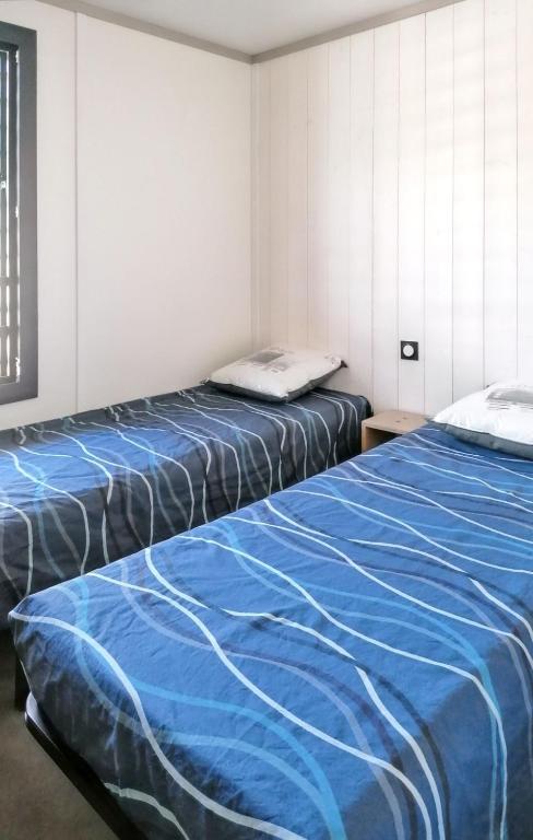 dwa łóżka siedzące obok siebie w pokoju w obiekcie Chalet enchanteur à Arzal avec vue sur lac et piscine partagée w mieście Arzal