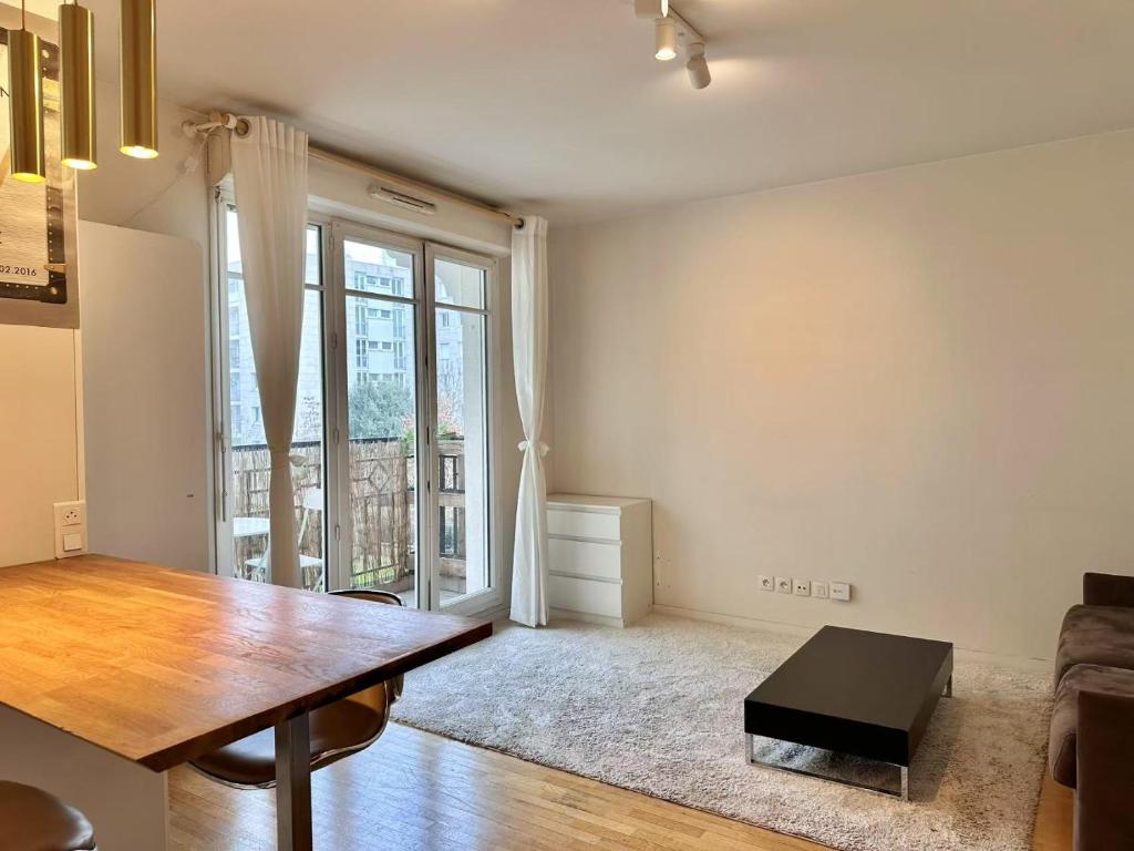un salon avec une table et une fenêtre dans l'établissement Appartement calm au maison des arts de Plessis, au Plessis-Robinson