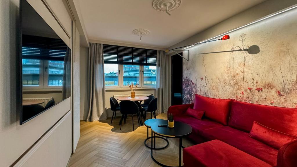 a living room with a red couch and a table at Apartament Acaia Old Town in Gdańsk