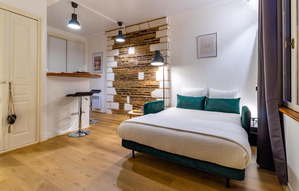 a bedroom with a bed and a brick wall at La Maison Verte -Hypercentre-confort in Troyes