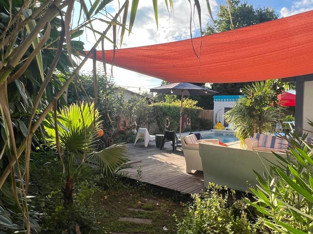 une cour avec une piscine et un parasol rouge dans l'établissement ARES - Maison le Paradis, à Arès