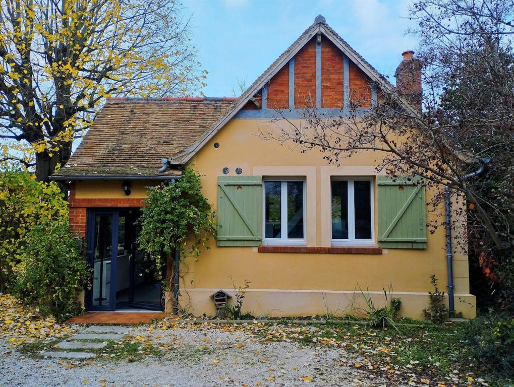 Une petite maison jaune avec volets verts dans l'établissement Maisonette au calme, à Saint-Pierre-du-Perray