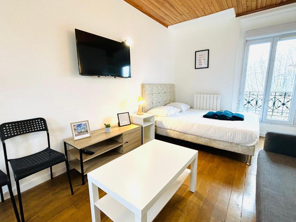 Zimmer mit einem Bett und einem Schreibtisch sowie einem Bett und einem Sofa in der Unterkunft Appartement porte de Saint Ouen in Paris