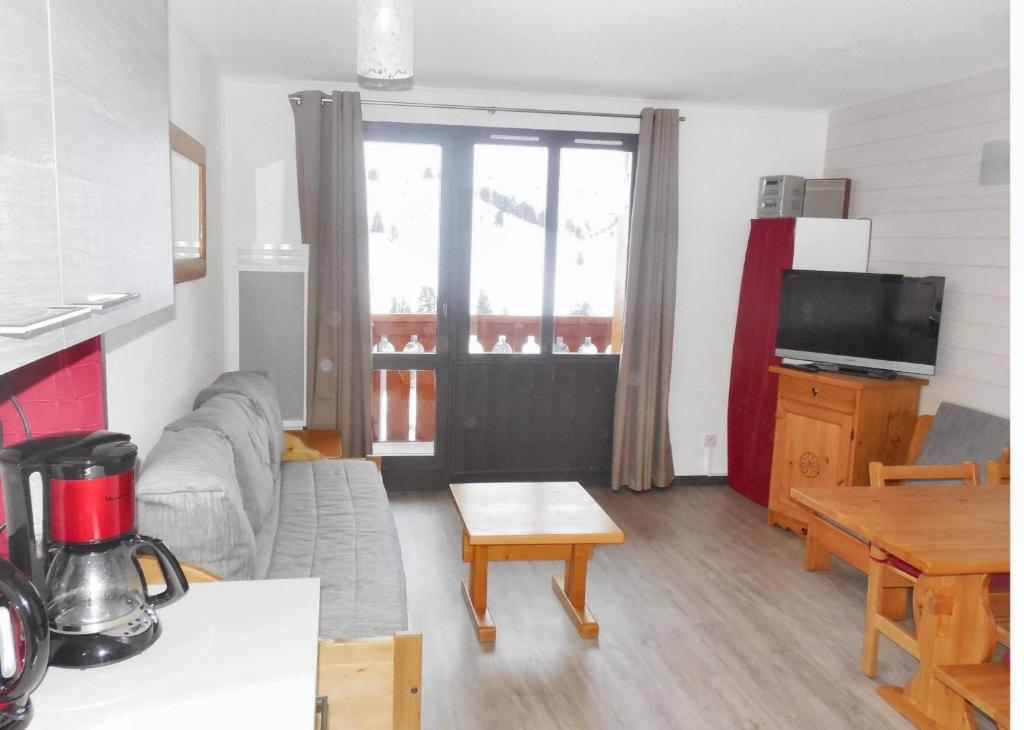 un salon avec un canapé et une table dans l'établissement Appartement charmant à La Plagne-Tarentaise avec balcon & vue, à La Plagne Tarentaise