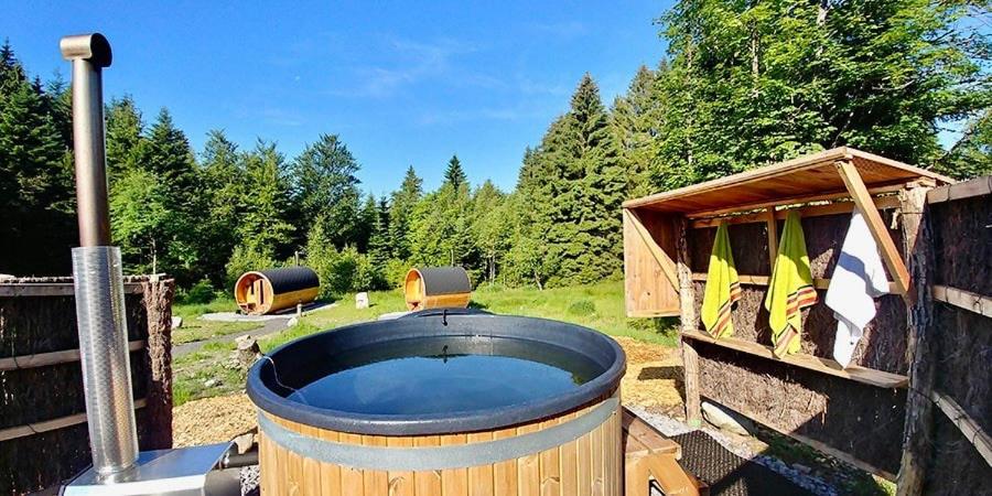 d'un bain à remous et d'une clôture en bois avec une maison en bois. dans l'établissement Le Grand Loup, appartement neuf avec bain nordique, à Gerbépal