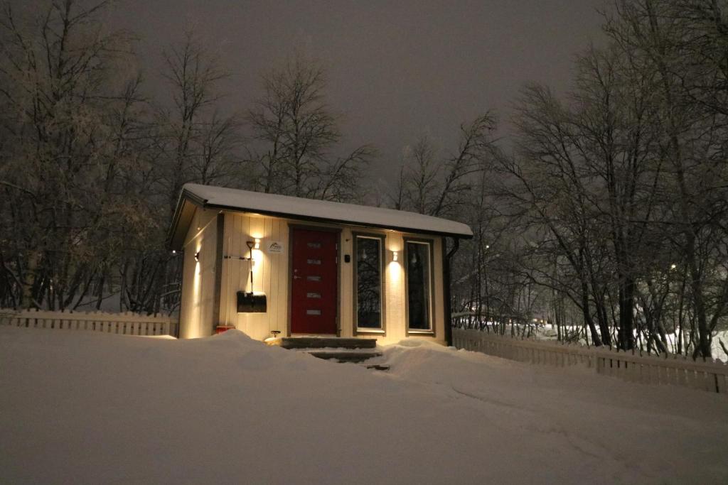a small building with lights in the snow at Aurora Cabin in Kiruna