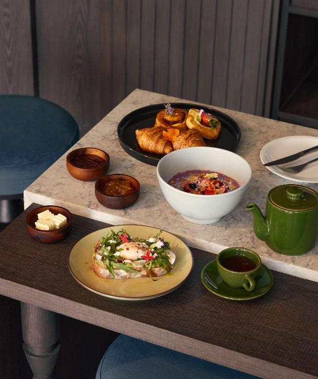 A plated breakfast spread with pastries, yogurt, salad, tea and condiments.