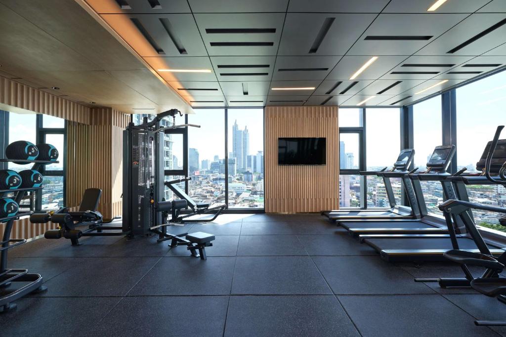 A bright hotel gym with treadmills, strength equipment and a city view.