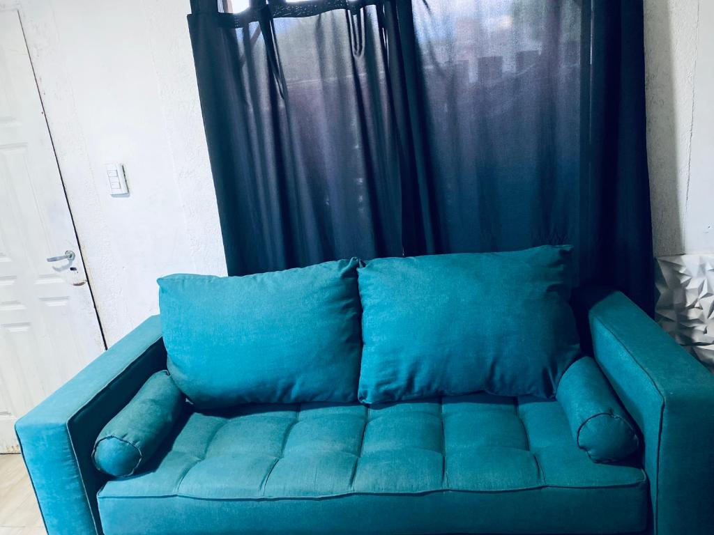 Un sofá azul con almohadas azules en una habitación. en Alquiler, en Colonia Las Rosas
