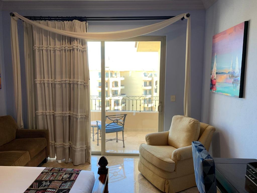 soggiorno con sedia e porta scorrevole in vetro di Medano Beach front resort Cabo Villa 2Queen beds 2805-B a Cabo San Lucas