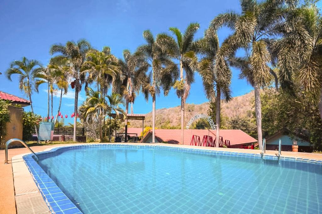 una piscina con palmeras y una montaña en Saitharn Iyara Resort, en Sai Yok