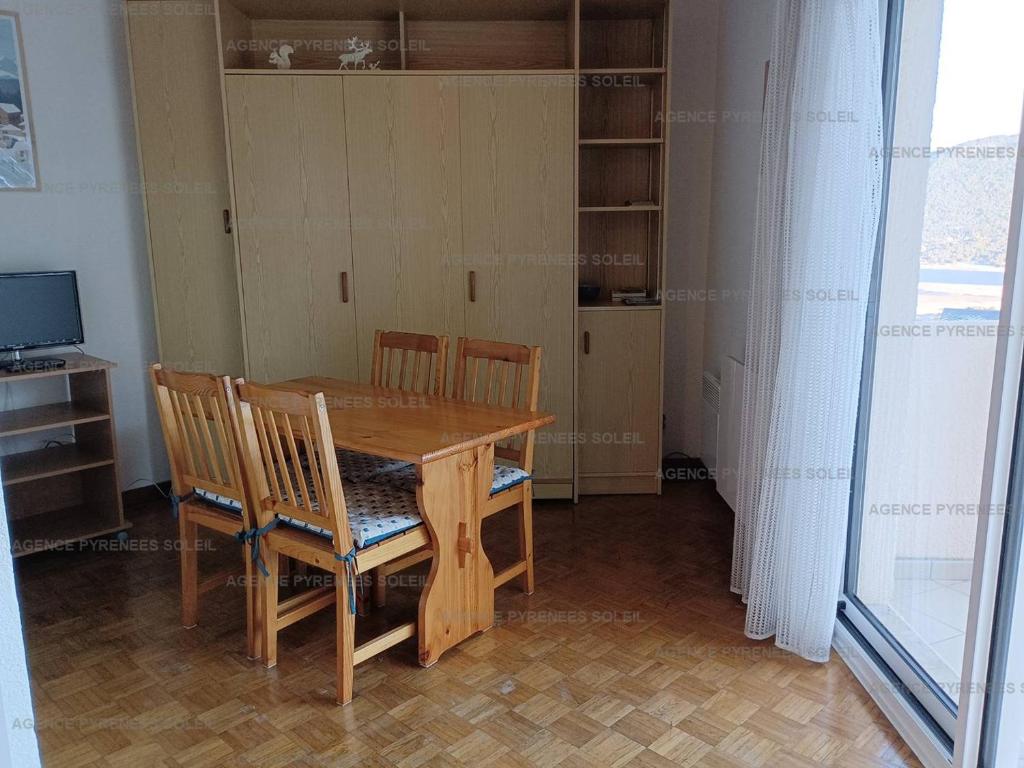 une salle à manger avec une table et des chaises en bois dans l'établissement Appartement lumineux avec balcon près du lac - FR-1-295-204, aux Angles
