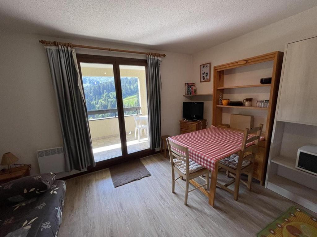 un salon avec une table et une grande fenêtre dans l'établissement Studio-cabine avec balcon proche pistes et parking - FR-1-787-113, à Laveissière